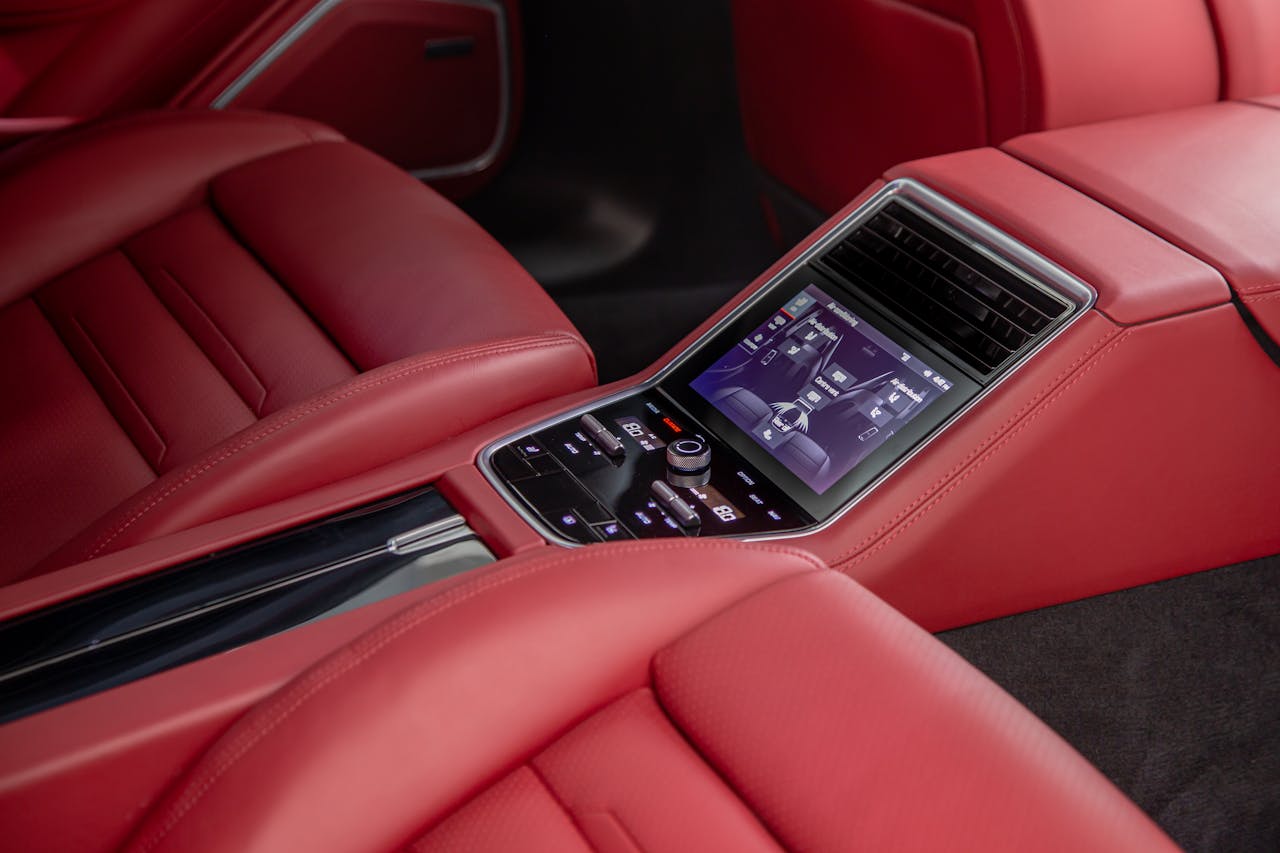 Close-up of a luxurious car interior with red leather seats and a touchscreen control panel.